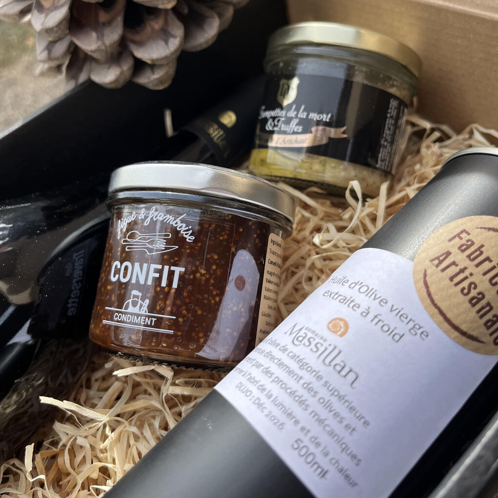 Détail d’un coffret cadeau du Domaine Massillan contenant un pot de confit figue & framboise, une huile d’olive BIO artisanale extraite à froid, et une préparation à la truffe, symbolisant le savoir-faire local et la qualité artisanale.