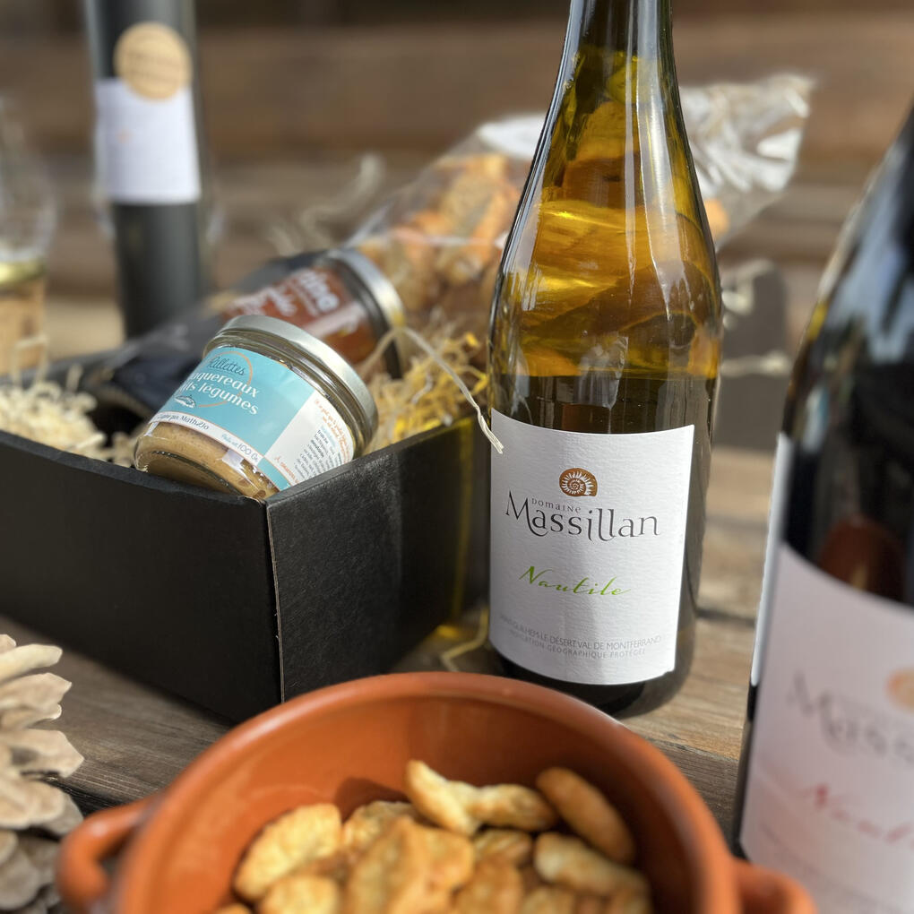 Vins bio et douceurs d’Occitanie Coffret cadeau du Domaine Massillan, composé de produits locaux et artisanaux : tartinables, biscuits croquants, huile d’olive bio du domaine et vins d’exception. À l’avant, la cuvée Nautile Blanc, un Chardonnay élevé 4 mois en fût de chêne.